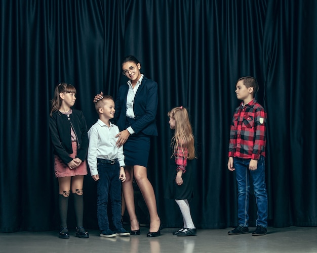 Enfants élégants Mignons Sur Fond Sombre De Studio. Les Belles Adolescentes Et Garçon Debout Ensemble