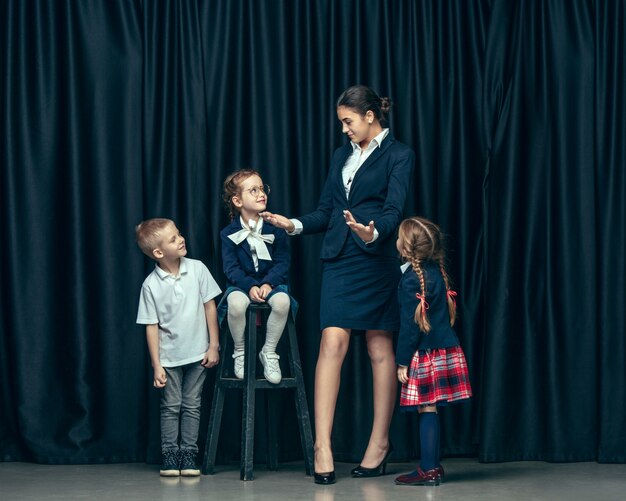 Enfants élégants mignons sur studio sombre. Les belles adolescentes et garçon debout ensemble