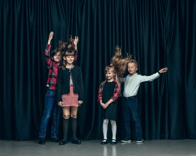 Enfants élégants mignons sur studio sombre. Les belles adolescentes et garçon debout ensemble