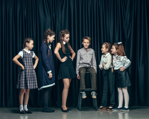 Enfants élégants mignons sur studio sombre. belles adolescentes et garçon debout ensemble