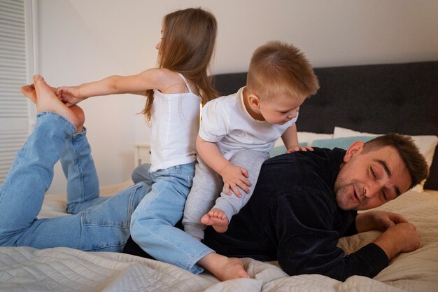 Les enfants font rire leur père en le chatouillant