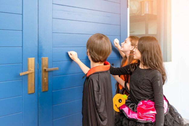 Enfants garçon et filles en costume d'Halloween se déguisent en train de frapper à la porte