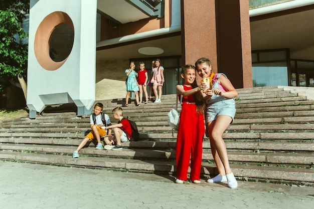 Enfants heureux jouant dans la rue de la ville en journée d'été ensoleillée devant un bâtiment moderne. Groupe d'enfants ou d'adolescents heureux s'amusant ensemble