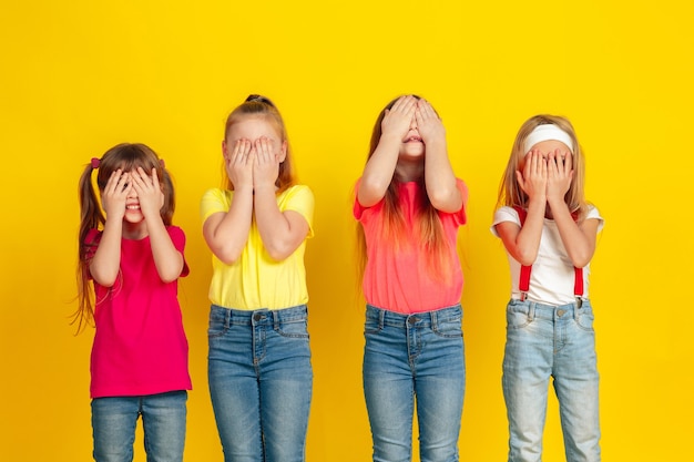 Enfants heureux jouant et s'amusant ensemble sur le mur jaune