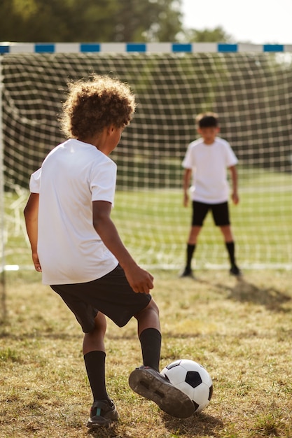 Photo gratuite enfants jouant au football supervisés par un entraîneur de football