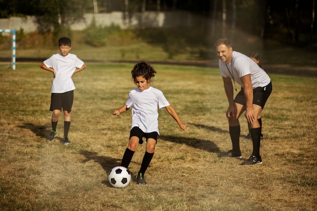 Photo gratuite enfants jouant au football supervisés par un entraîneur de football