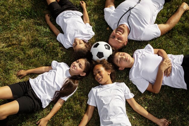 Photo gratuite enfants jouant au football supervisés par un entraîneur de football