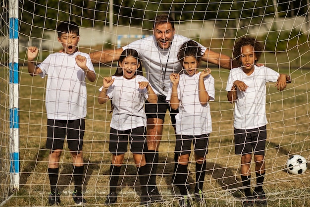 Enfants jouant au football supervisés par un entraîneur de football