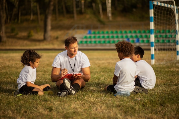 Enfants jouant au football supervisés par un entraîneur de football