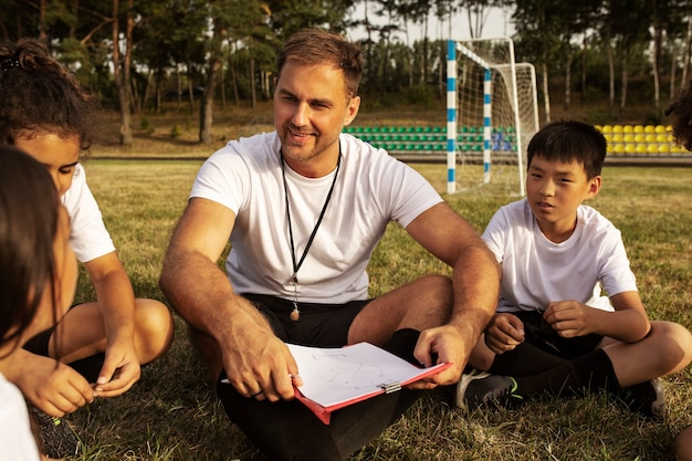 Photo gratuite enfants jouant au football supervisés par un entraîneur de football