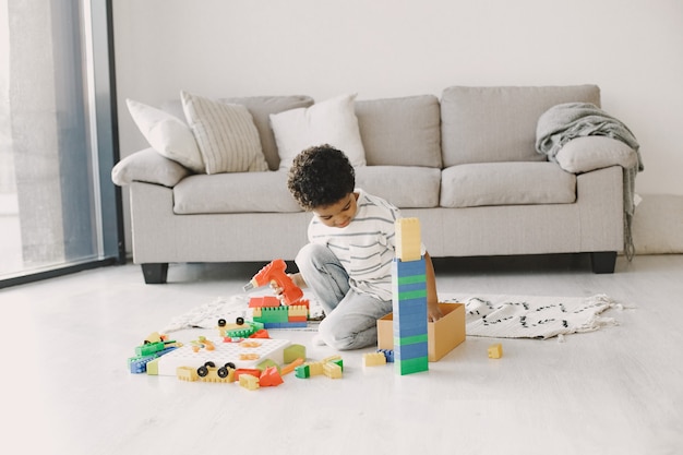 Photo gratuite les enfants jouent à des jeux sur le sol. un enfant africain compose un constructeur. cheveux bouclés chez un garçon.