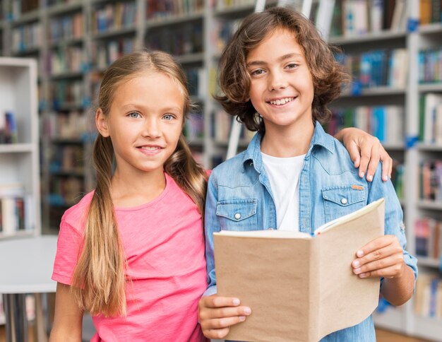 Enfants lisant un livre ensemble dans la bibliothèque