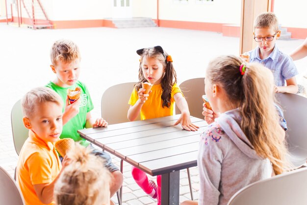 Enfants mangeant de la crème glacée dans un café en plein air