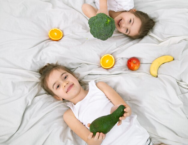 Des enfants mignons heureux jouent avec des fruits et légumes. Une alimentation saine pour les enfants.