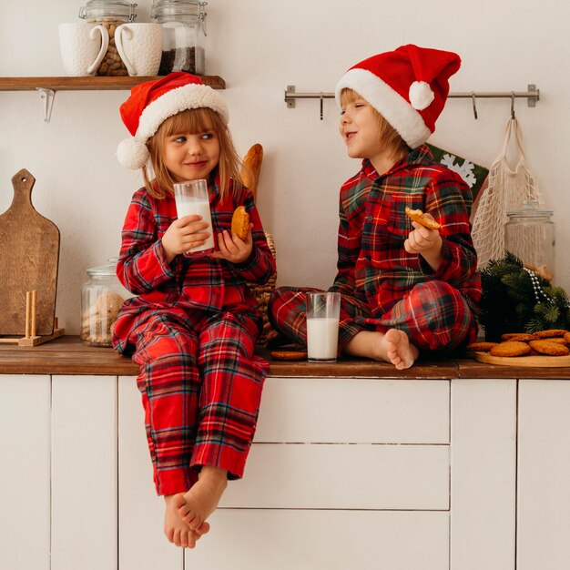 Enfants mignons, manger des biscuits de Noël et boire du lait