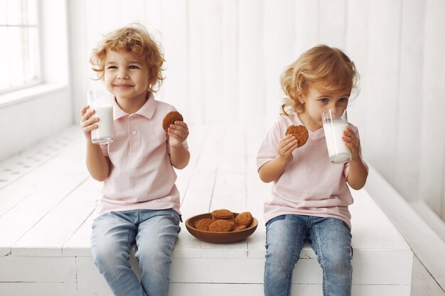 Enfants mignons manger des cookies et boire du lait