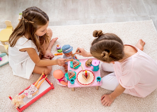 Photo gratuite enfants non binaires jouant à un jeu d'anniversaire avec des poupées