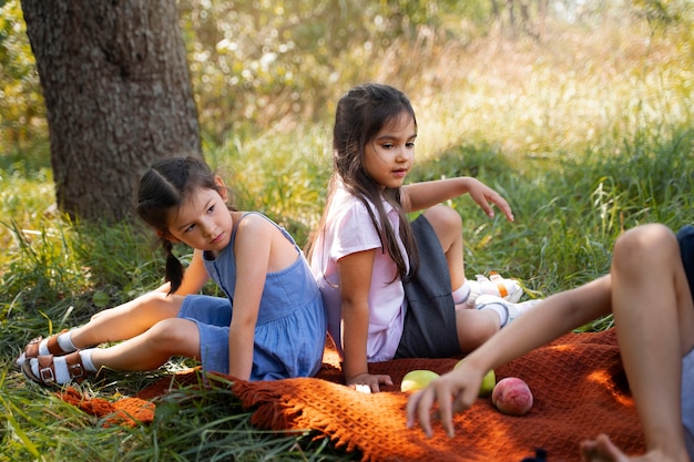 Photo gratuite les enfants passent du temps ensemble à l'extérieur sur une couverture profitant de l'enfance