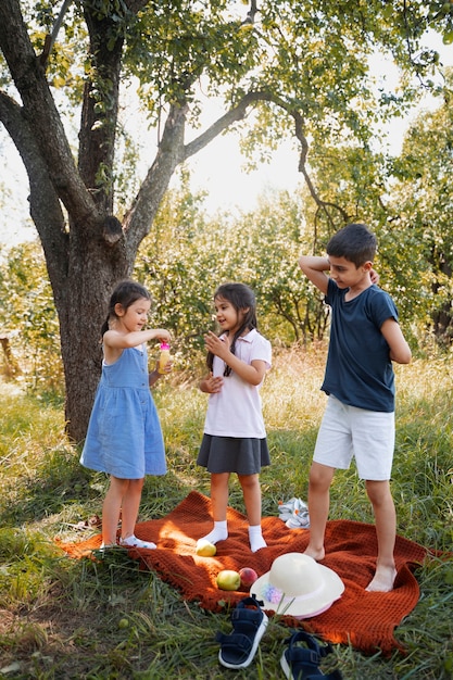 Photo gratuite les enfants passent du temps ensemble à l'extérieur sur une couverture profitant de l'enfance