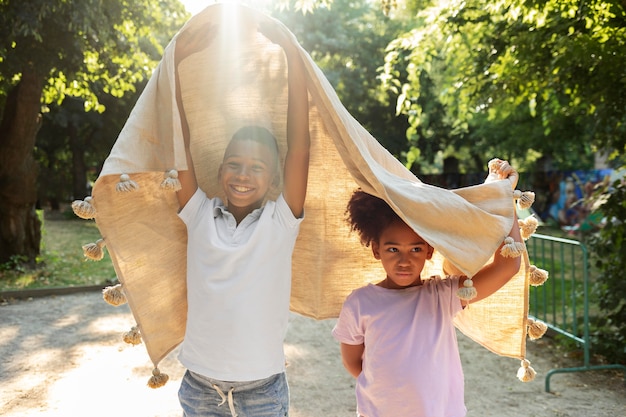 Des enfants de plan moyen jouant avec une couverture