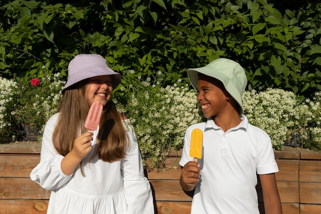 Enfants de plan moyen mangeant de la crème glacée