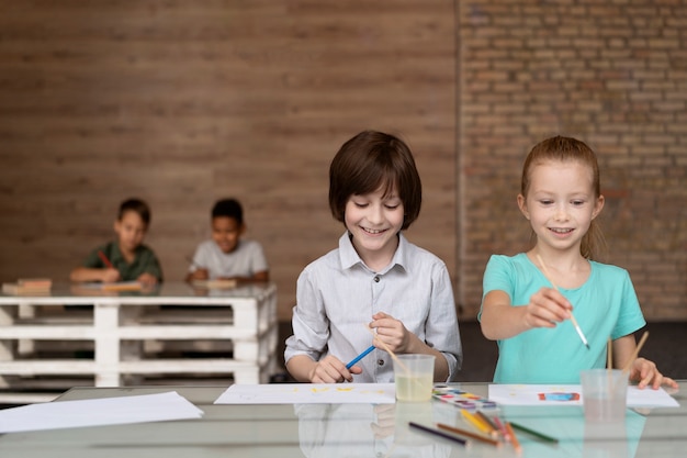 Photo gratuite enfants à plan moyen peignant ensemble