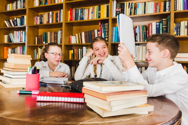 Enfants qui rient en regardant copybook dans la bibliothèque