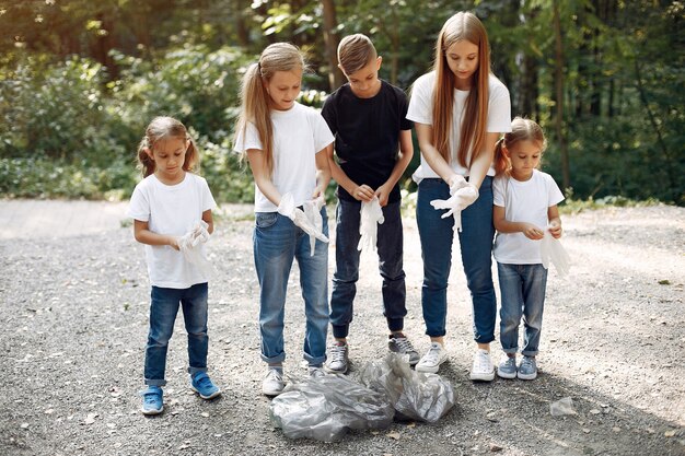 Enfants ramassent les ordures dans des sacs à ordures dans le parc