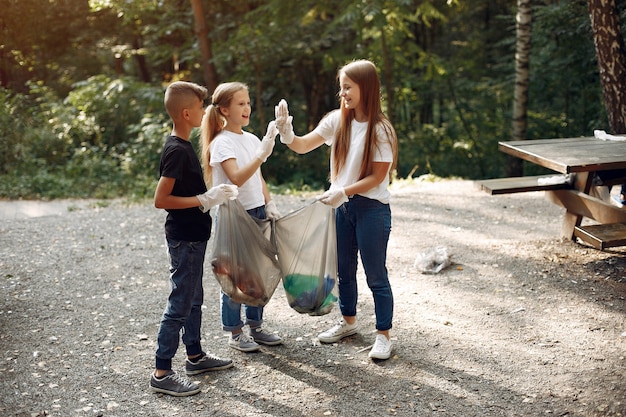 Enfants ramassent les ordures dans des sacs à ordures dans le parc