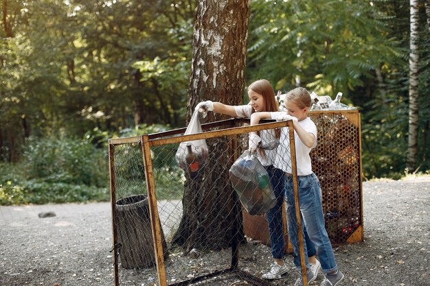 Enfants ramassent les ordures dans des sacs à ordures dans le parc