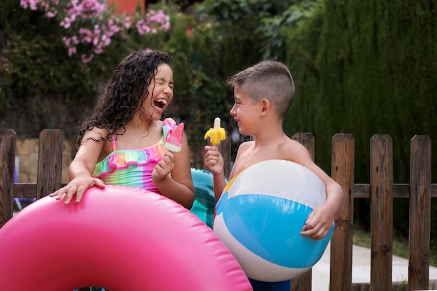 Photo gratuite enfants s'amusant avec flotteur au bord de la piscine
