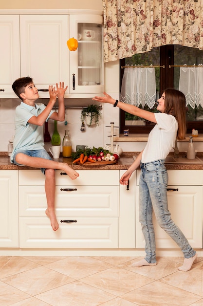 Enfants s'amusant avec des légumes dans la cuisine