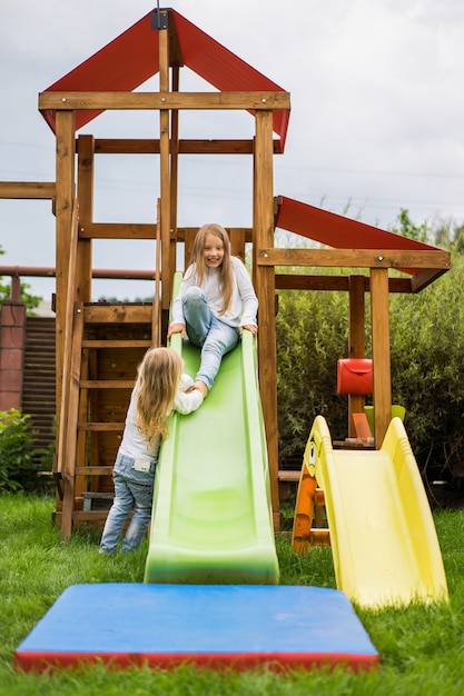 les enfants sortent du toboggan, les sœurs jouent ensemble dans le jardin