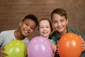 Photo gratuite enfants souriants de plan moyen avec des ballons