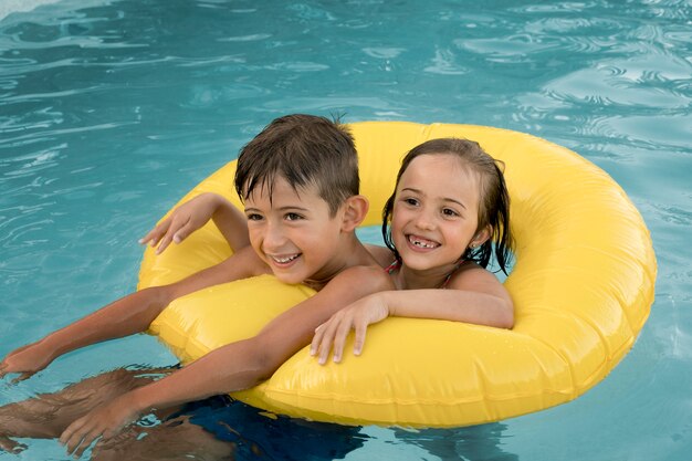 Enfants souriants de plan moyen avec bouée de sauvetage