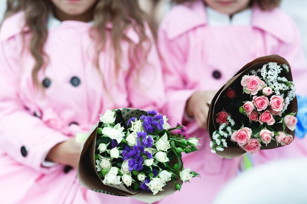 Les enfants tiennent des bouquets roses et violets