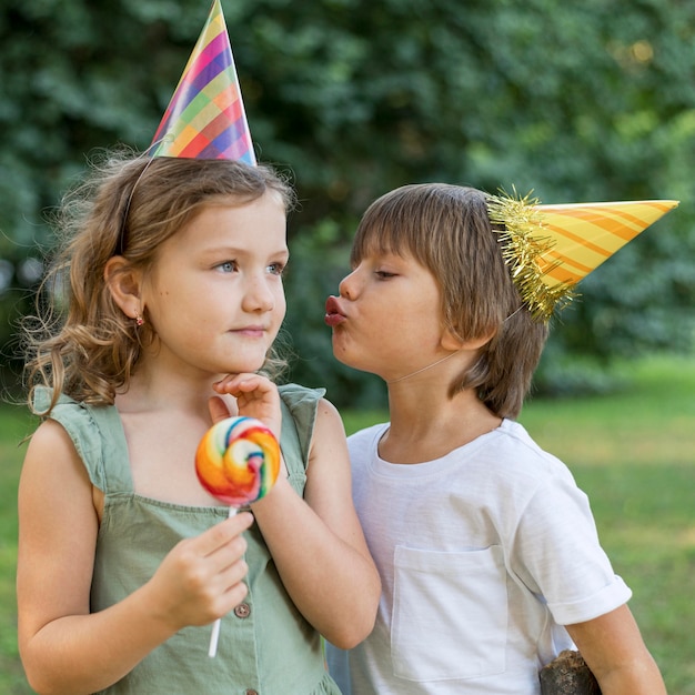 Enfants de tir moyen avec des chapeaux de fête à l'extérieur