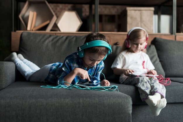 Enfants utilisant des tablettes sur le canapé