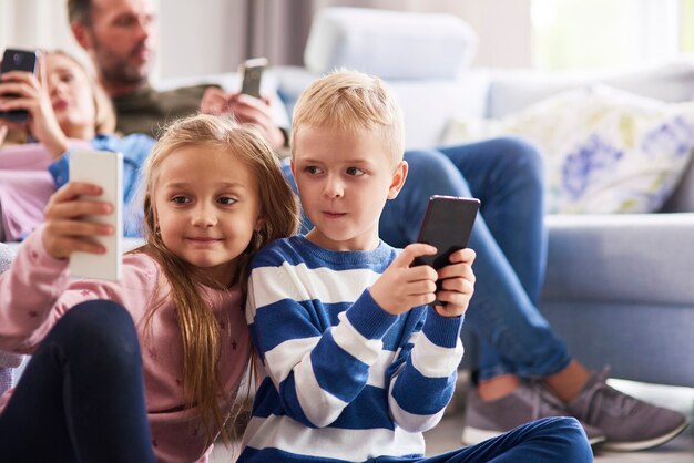 Enfants utilisant un téléphone portable dans le salon