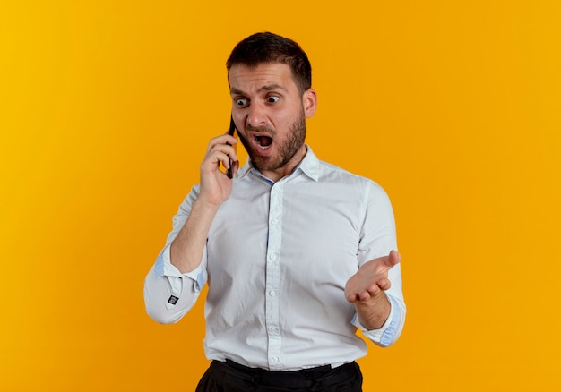 Photo gratuite ennuyé bel homme parle au téléphone crie à quelqu'un isolé sur un mur orange