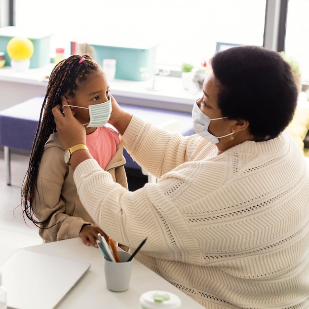 Enseignant aidant un élève à mettre un masque médical