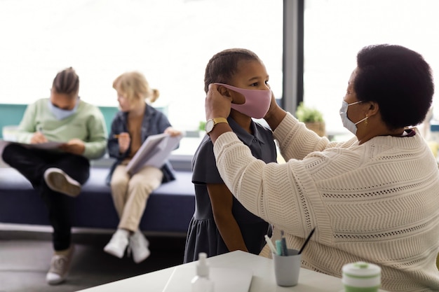 Enseignant aidant un élève à mettre un masque médical