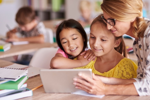 Photo gratuite enseignant aidant les élèves avec tablette numérique