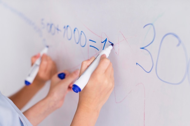 Enseignant et étudiant faisant le calcul sur un tableau blanc