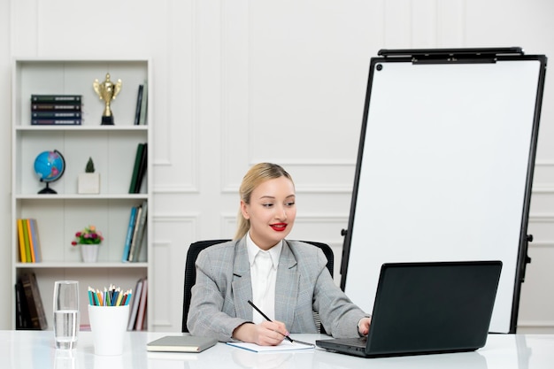 Enseignant jeune instructeur mignon en costume en classe avec ordinateur portable et tableau blanc en tapant