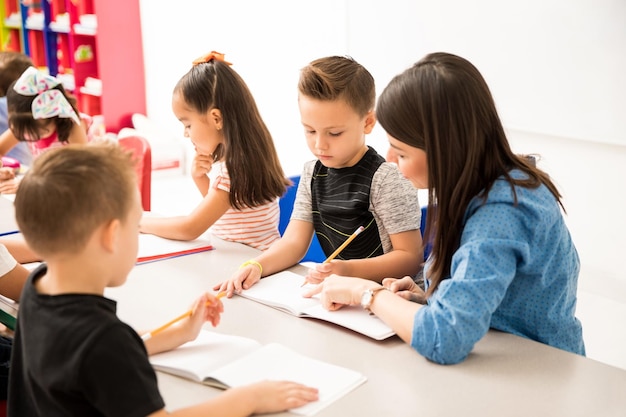 Enseignant préscolaire expliquant un devoir d'écriture à l'un de ses élèves dans une salle de classe