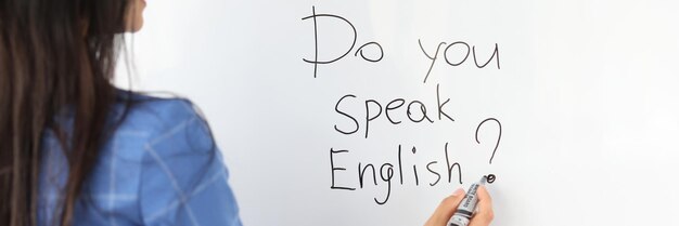 Une enseignante écrit avec un marqueur parlez-vous anglais sur un tableau blanc en tant que concept de traducteur