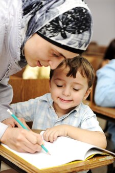 Enseignante musulmane aidant un petit élève en classe