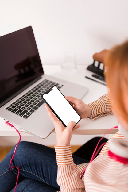 Enseignante utilisant un ordinateur portable et un smartphone pendant les cours en ligne