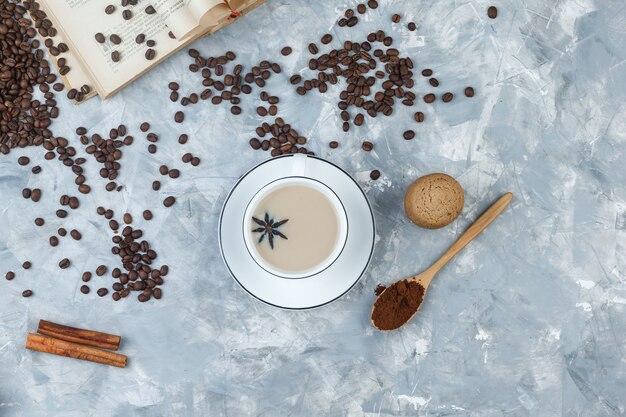 Ensemble de biscuits, grains de café, café moulu, livre, épices et café dans une tasse sur un fond de plâtre gris. vue de dessus.